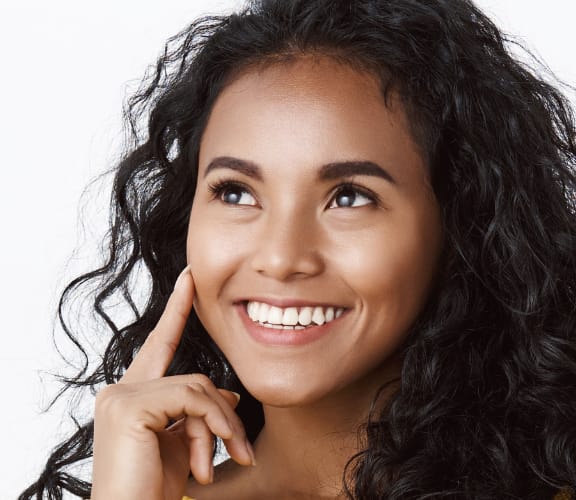 Woman looking up and pointing at her face like she is thinking