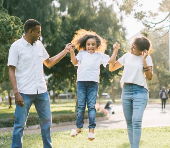 Mother and father holding childs hand and lifting them up into the air